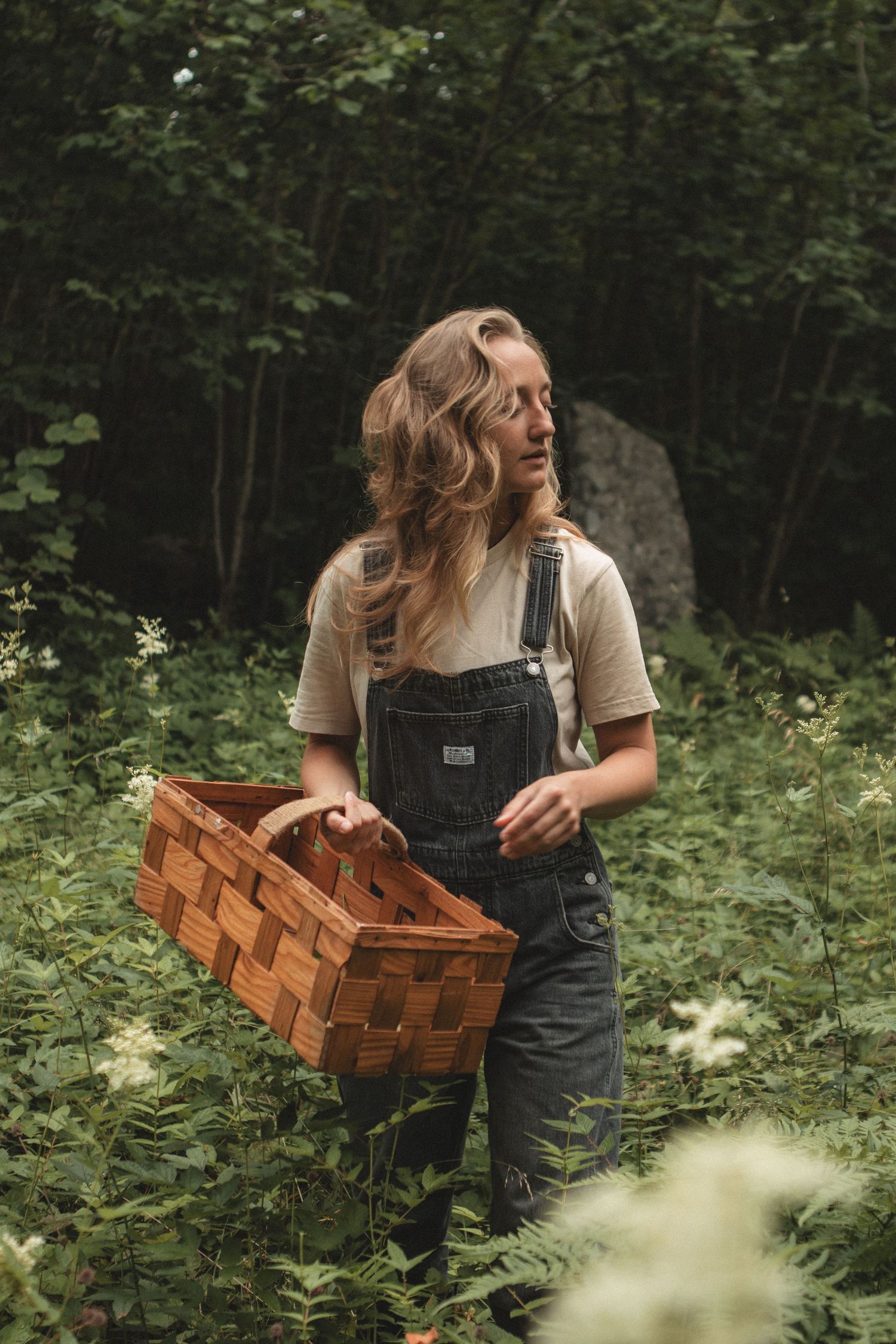Country style portrait in denim overalls and brown hat at rustic wooden doorway.