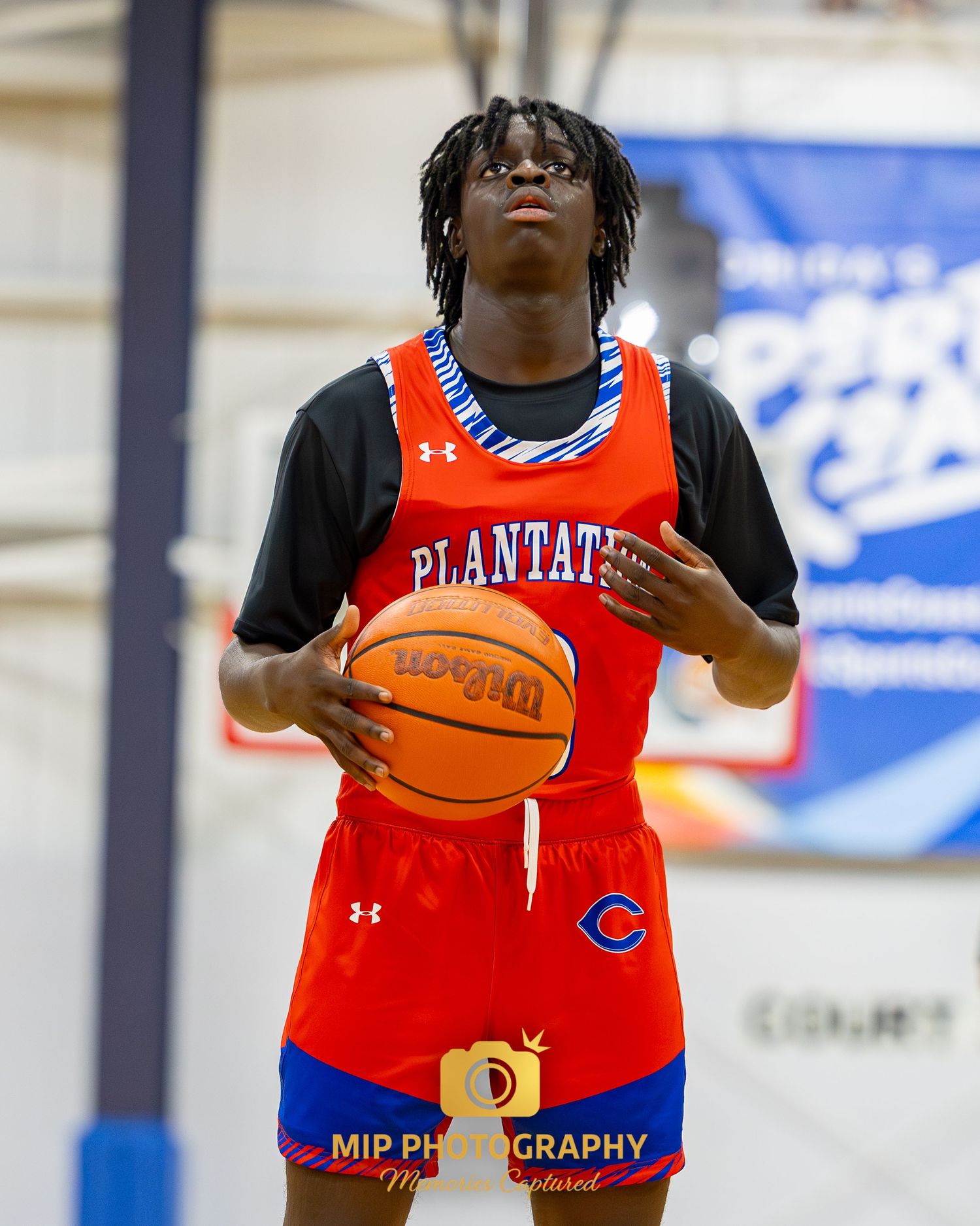 A basketball player in a red Plantation uniform holds a basketball during a game.
