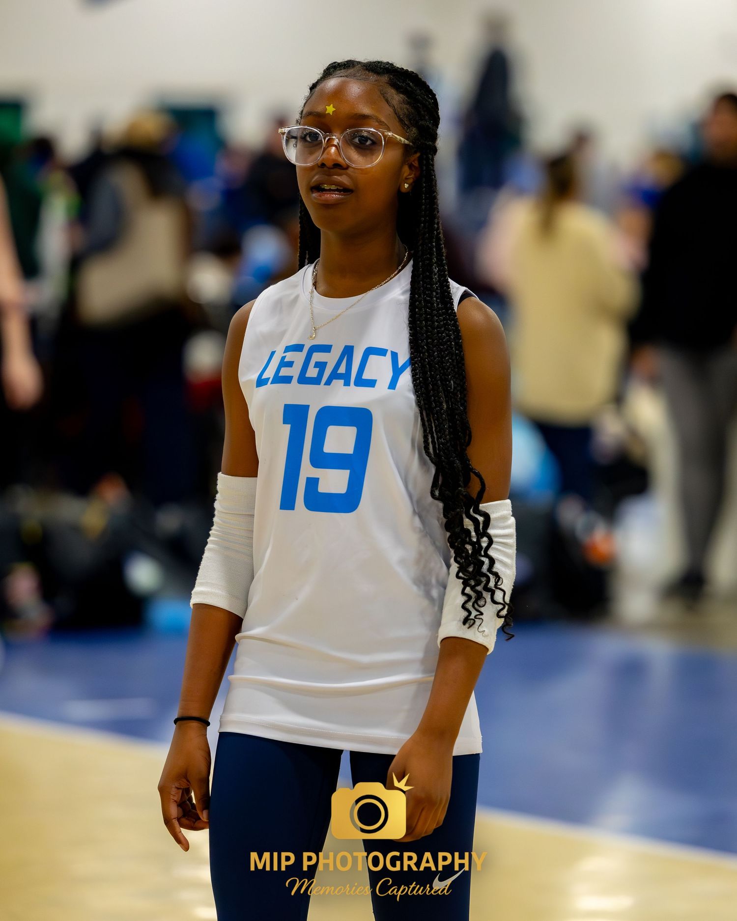 A volleyball player wearing a white Legacy jersey with number 19 stands ready on the court.
