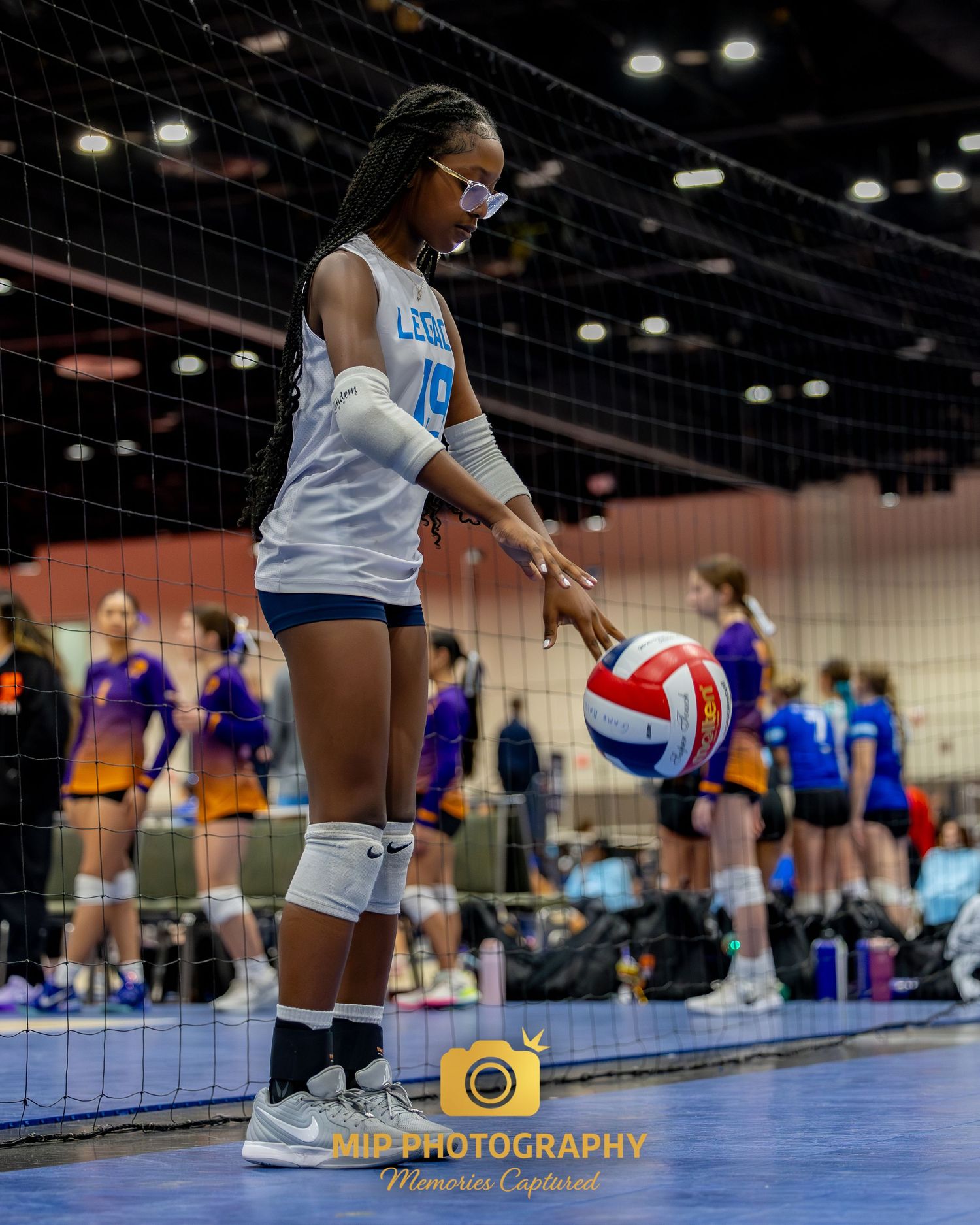 Volleyball players practice defensive drills on the court during an indoor training session.