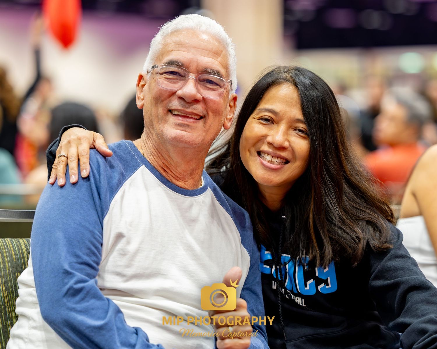 People smile and pose together at a casual indoor gathering wearing blue and white attire.