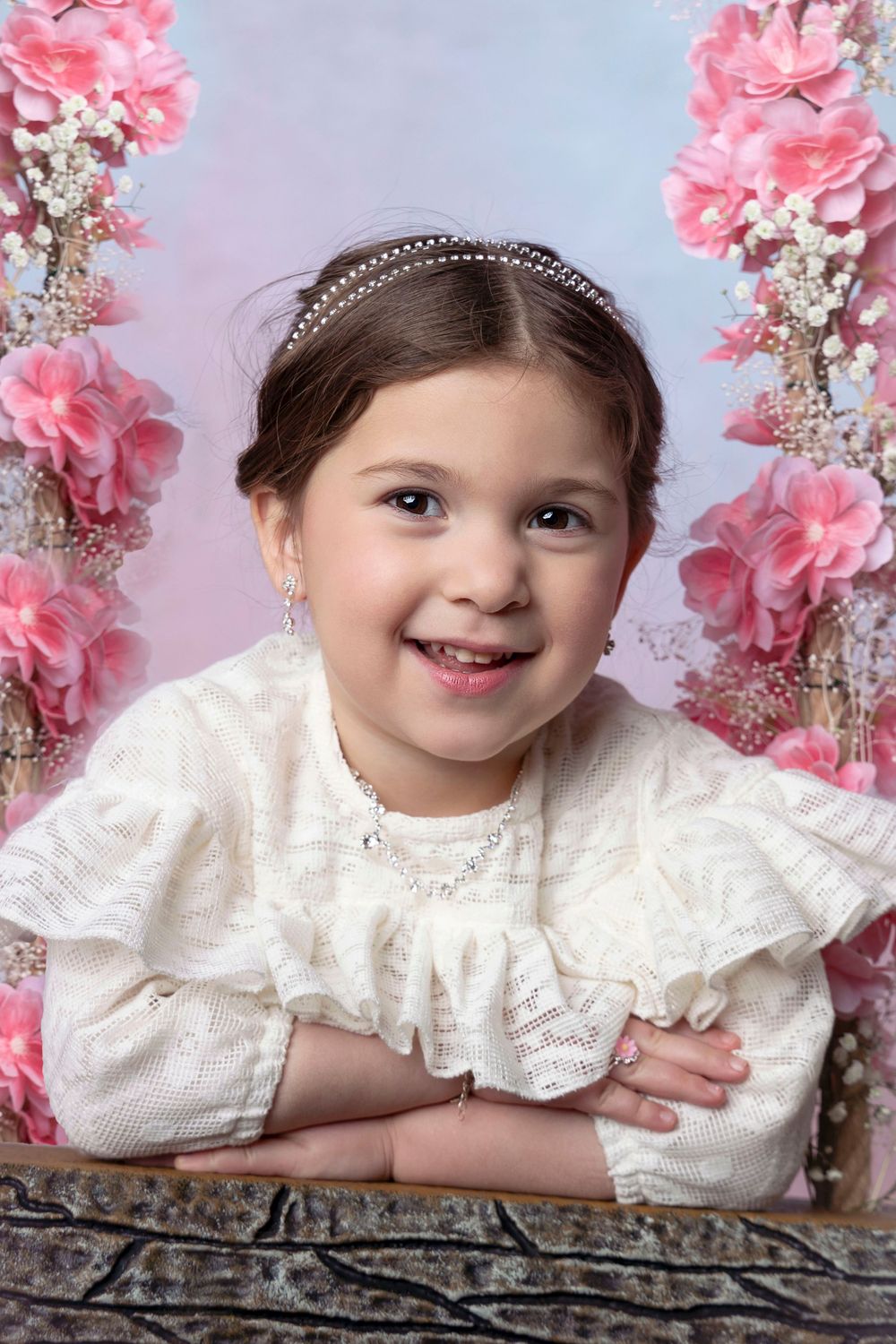 Sweet portrait with pink floral decorations and white lace dress with ruffled collar.