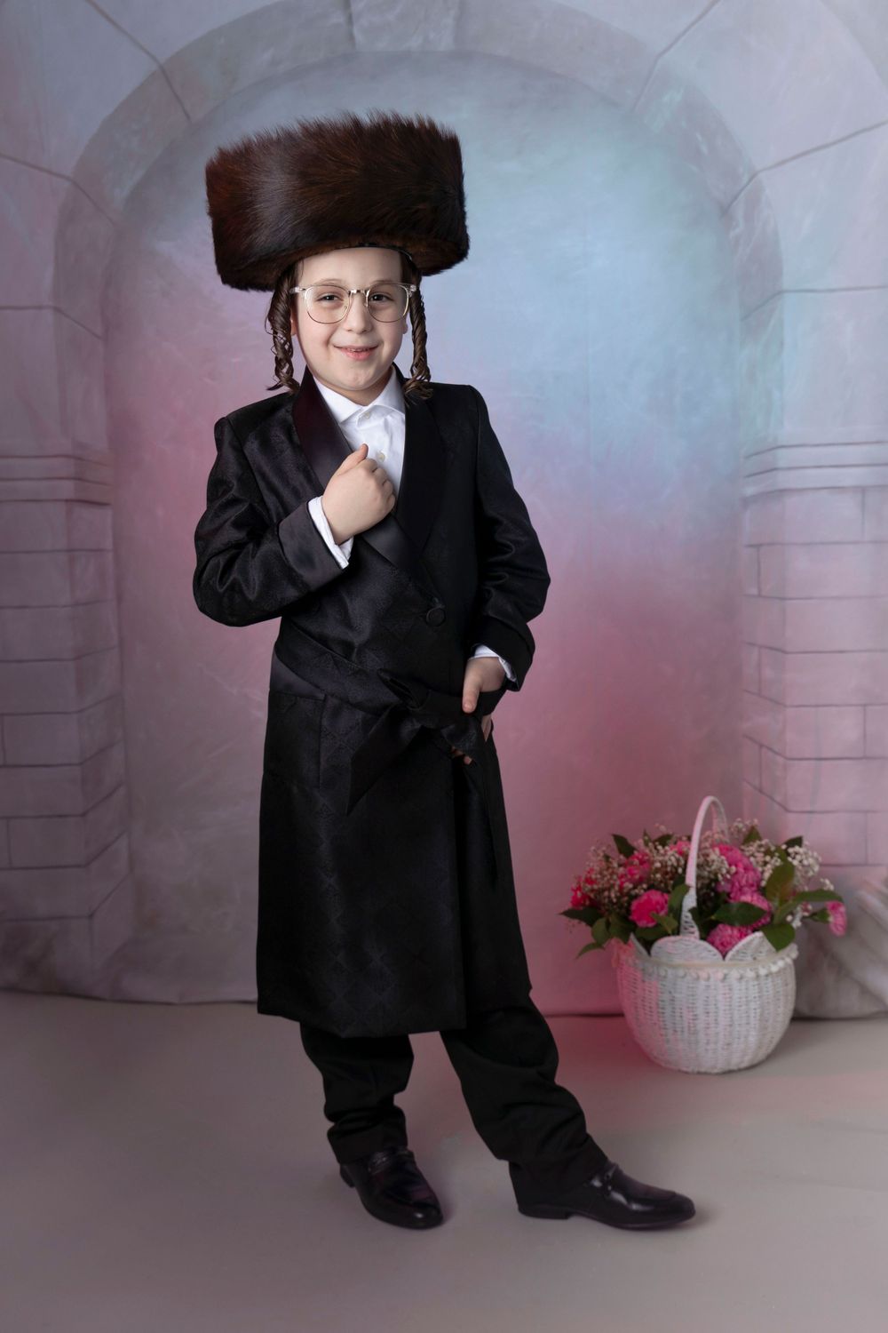 Traditional portrait in black suit and fur hat with flower basket in background.