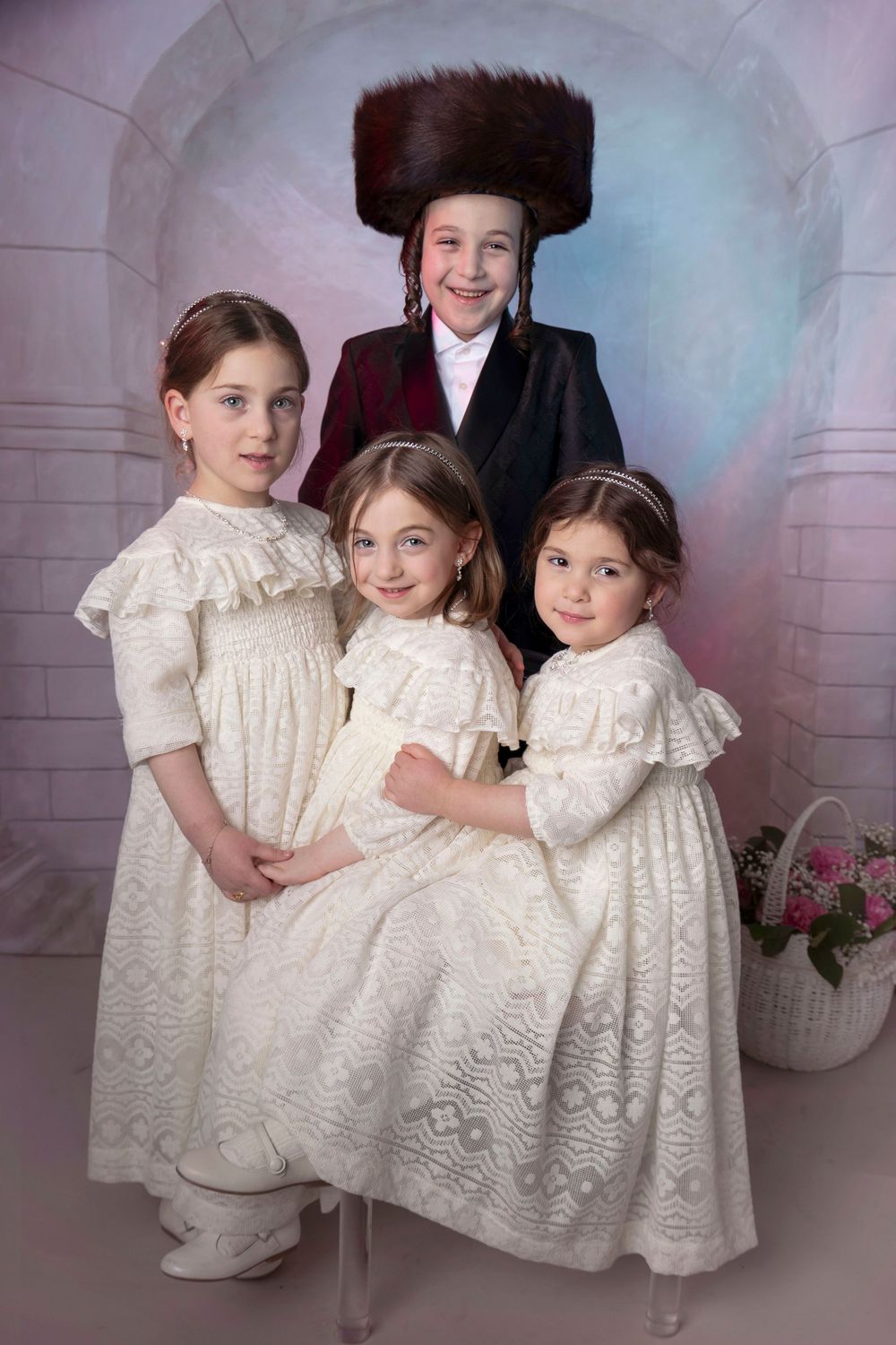 Portrait of young children dressed up as kallah's with boy wearing shtreimel, dressed up as chusson in archway setting. Purim photo.