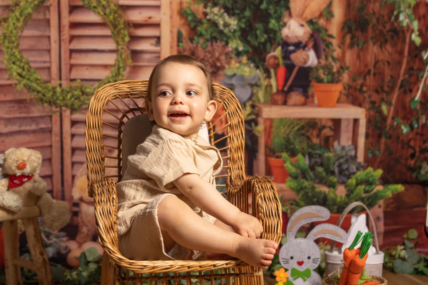 Toddler sitting in wicker chair with festive fall decorations and stuffed animals.
