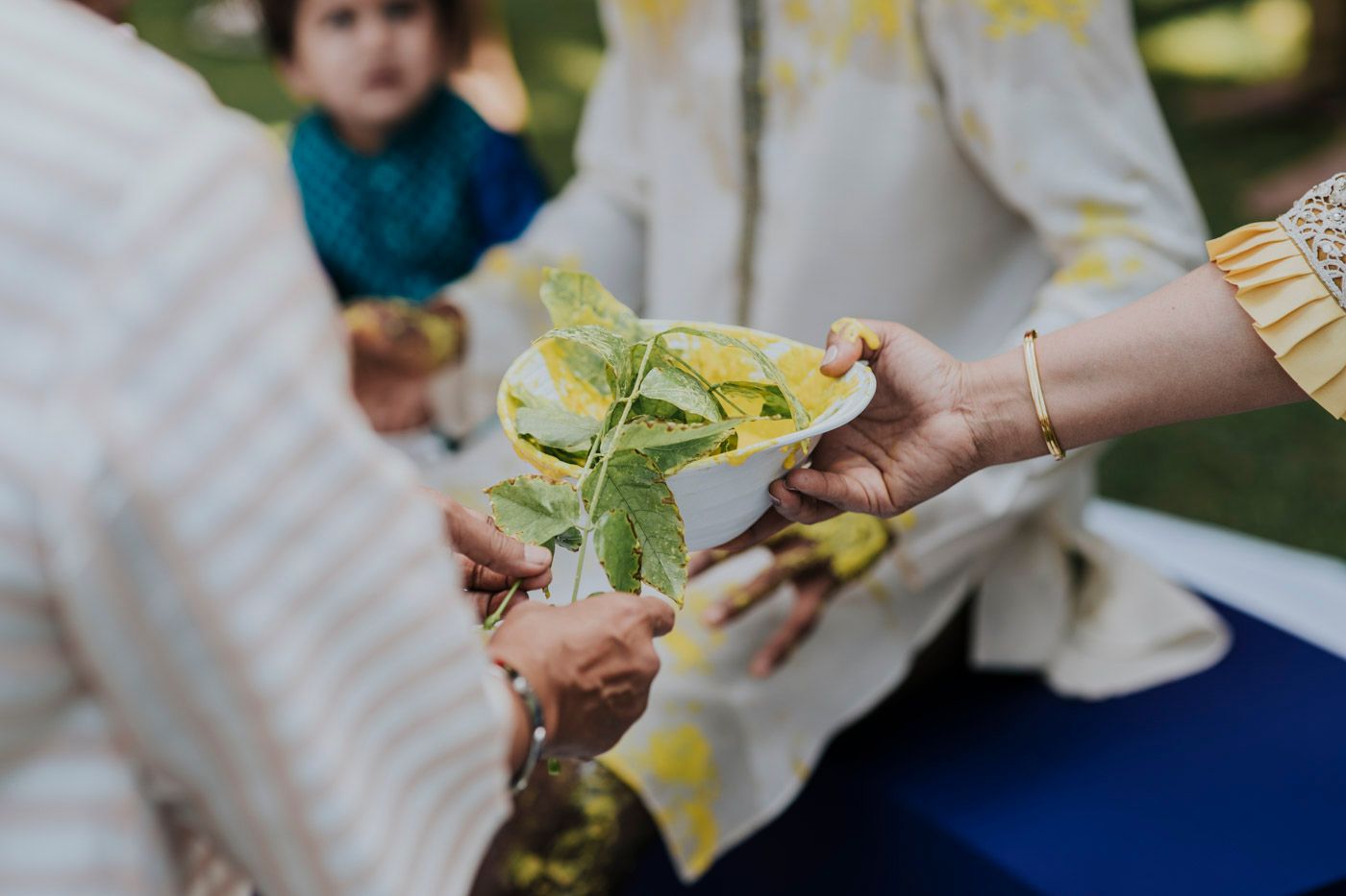 Hands passing a green leaf during an outdoor nature education activity with a blurred background.