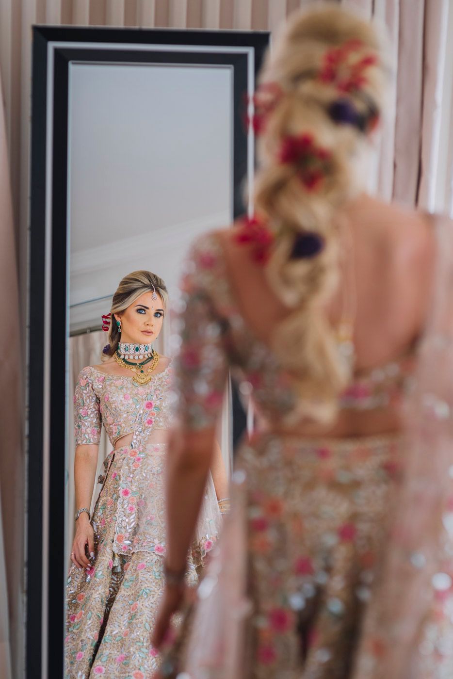 Ornate traditional dress with floral embellishments reflected in a large framed mirror.