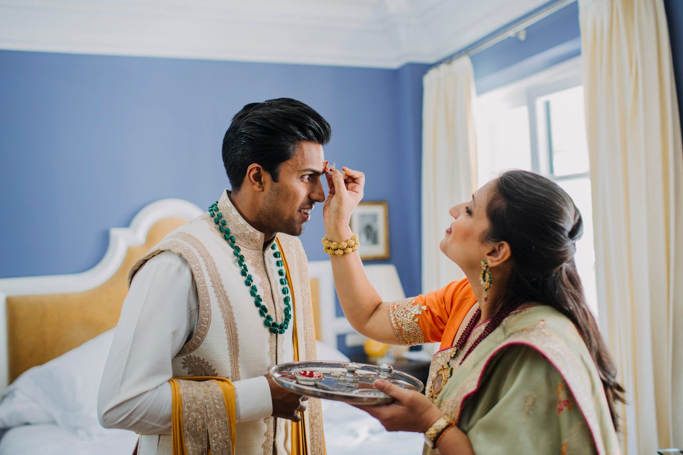 Traditional South Asian pre-wedding ritual showing a ceremonial blessing between two people in colorful attire.