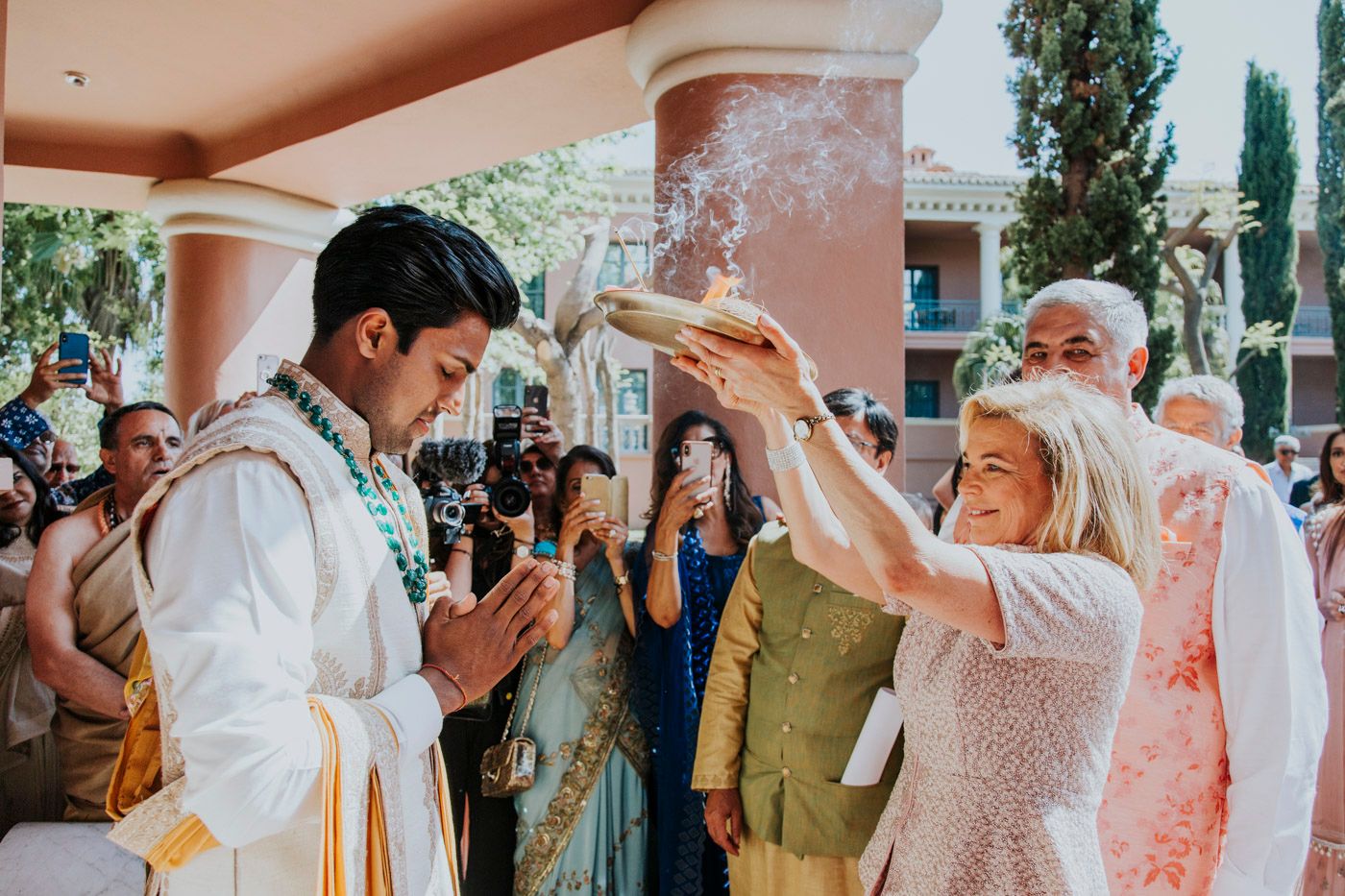 A joyful wedding celebration with guests throwing flower petals during a traditional cultural ceremony.