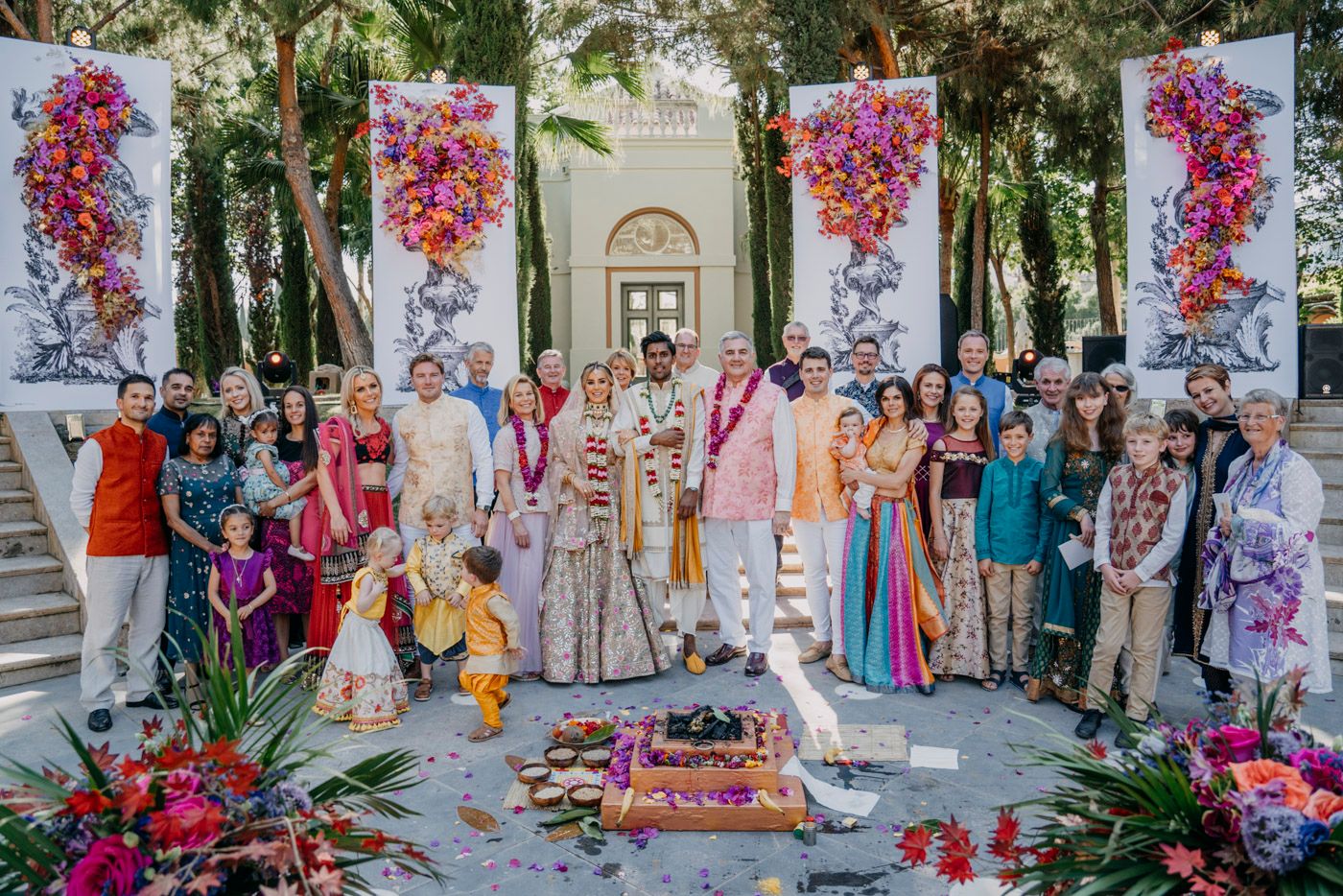 Outdoor wedding ceremony with floral decorations featuring bright pink blooms and elegant white arches in a garden setting.
