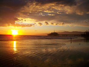 Stunning sequence of ocean sunset views with dramatic clouds and a pier silhouetted against the golden sky.