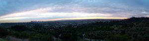 Panoramic view of a city skyline at dusk with clouds stretching across the horizon.