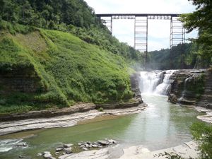 Series of views showing a powerful waterfall flowing through a scenic river gorge with steep rock walls.