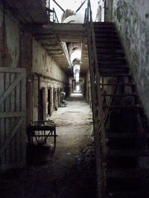 Dark, eerie corridor views inside an abandoned prison with deteriorating cells and walkways.