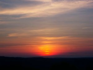 Dramatic sunset sky with orange and pink clouds stretching across the horizon.