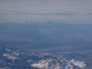 Vast mountain ranges with snow-dusted peaks extend into the distant horizon under clear skies.