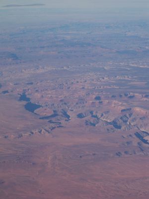Aerial view of desert canyons and plateaus stretching across the arid landscape.