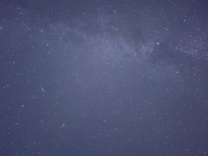 Starry night sky showing faint clouds and scattered stars across dark blue space.