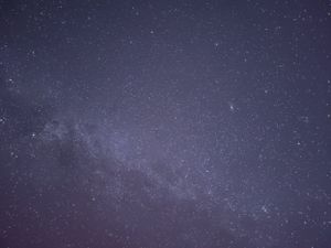 Deep blue night sky filled with countless twinkling stars and a subtle purple hue.