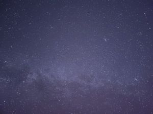 Brilliant starfield stretching across the night sky with purple and blue cosmic hues.