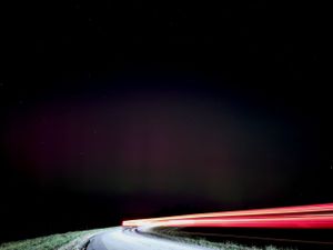 Dark horizon with streaking red light trails creating dramatic patterns in the night sky.