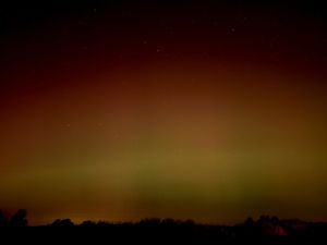 Reddish-orange glow on the horizon transitions to yellow under a dark night sky.