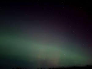 Ethereal green northern lights dance across the dark night sky.