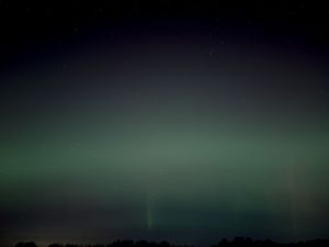 Soft green aurora borealis display stretching horizontally across the night horizon.