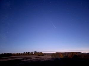 Starlit night sky stretches across the horizon over a dark rural landscape.