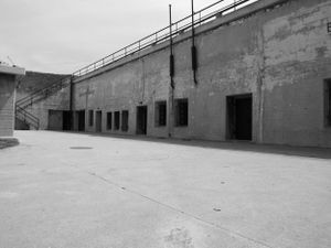 Long concrete wall with metal railings at an abandoned prison facility.
