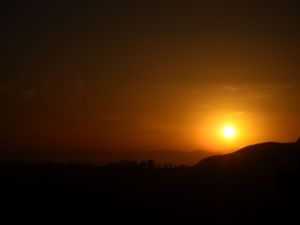 Orange sunset over mountain silhouettes with vibrant sky gradients.