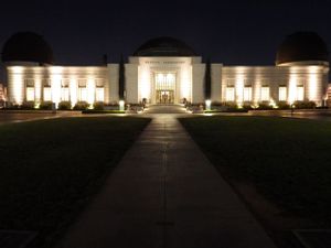 Illuminated modern building facade at night with glowing windows and walkway.