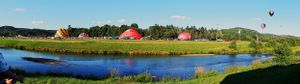 Panoramic landscape view of red barns and farm buildings nestled in green rolling hills.