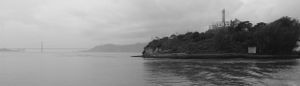 Panoramic view of a misty coastline with mountains and water in black and white.