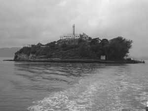 Panoramic black and white seascape showing a rocky peninsula extending into calm waters.