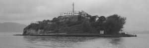Panoramic coastal scene with rocky cliffs and water in monochrome tones.
