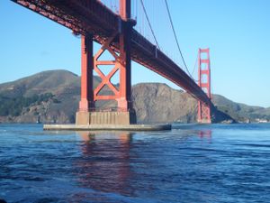 Golden Gate Bridge spans across blue waters with its iconic red towers and suspension cables.