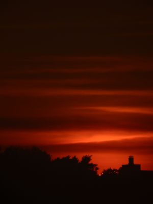 Dramatic red and orange sunset sky with dark silhouettes on the horizon.