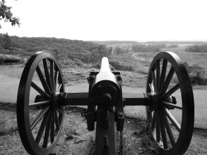 Historic cannons lined up on battlefield overlooking valley landscape.