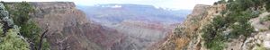 Panoramic view of the Grand Canyon's layered red rock formations and deep valleys stretching to the horizon.