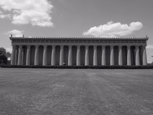 Panoramic view of a neoclassical building with multiple columns under a bright sky.