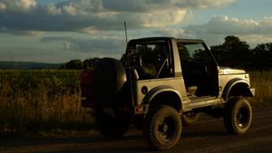 Vintage off-road vehicles parked in a field during golden hour.