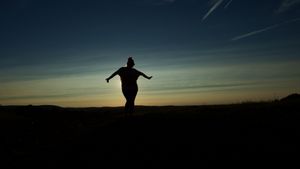 Silhouettes of people against dramatic sunset sky on hilltop.