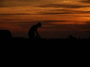 Silhouettes of mountains against a dramatic orange sunset sky create a stunning natural landscape.