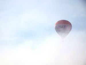 A white hot air balloon appears faintly against an overcast sky with soft lighting.