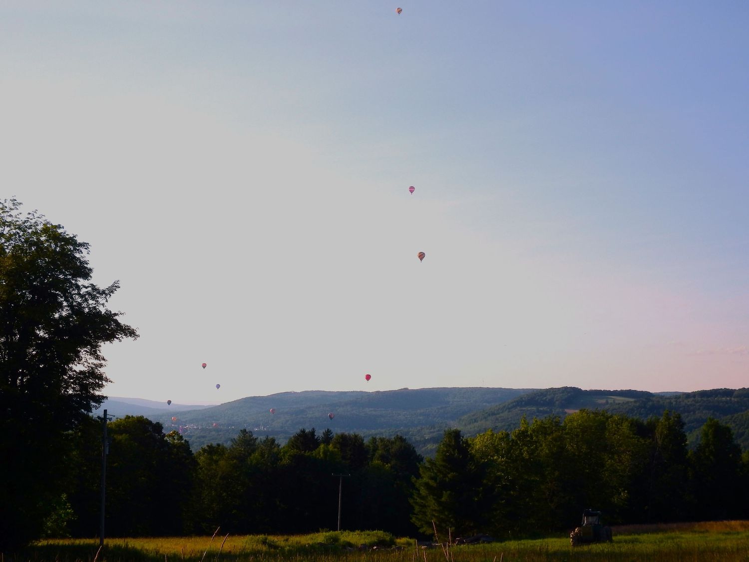 Colorful hot air balloons rising over a mountain landscape at dawn.