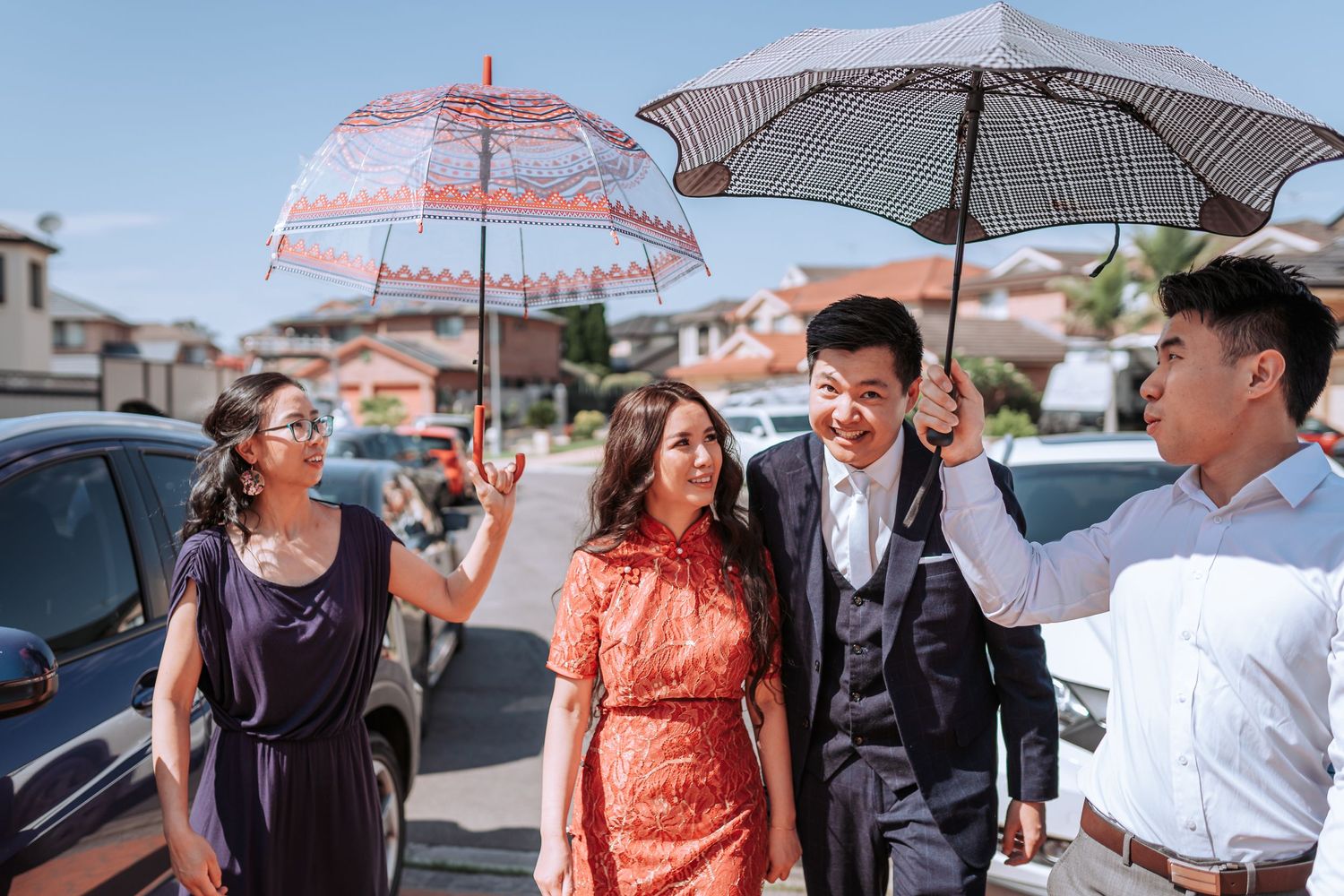 A group walking down a street on a sunny day carrying decorative umbrellas.