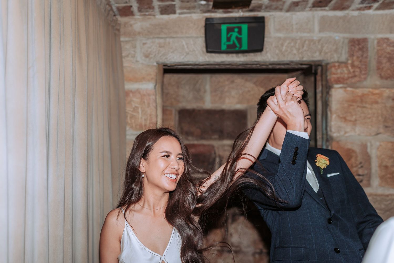 A joyful dancing moment captured during a wedding celebration in a rustic venue.