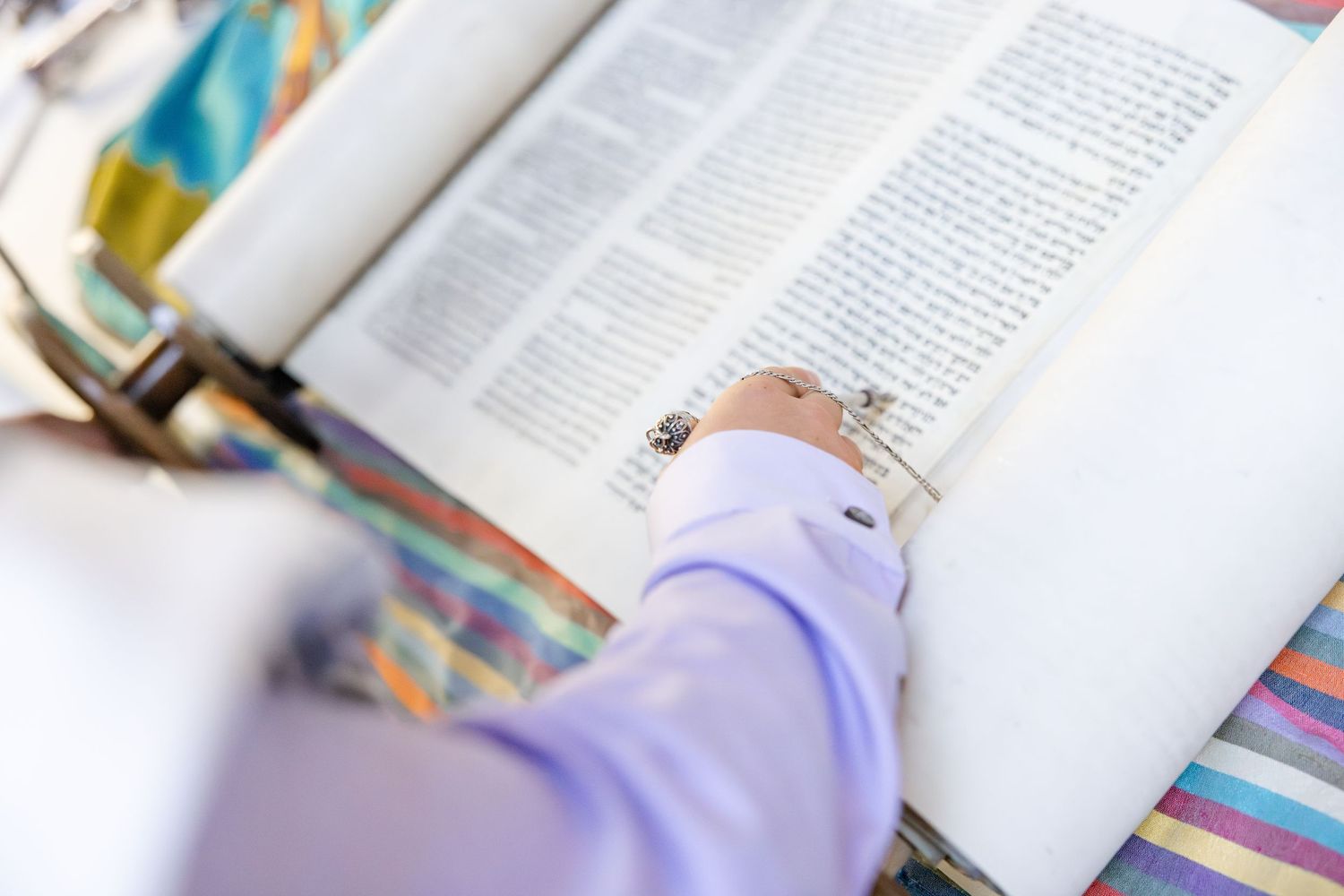 Hand in purple sleeve pressing engagement ring on open book page in a wedding proposal moment.