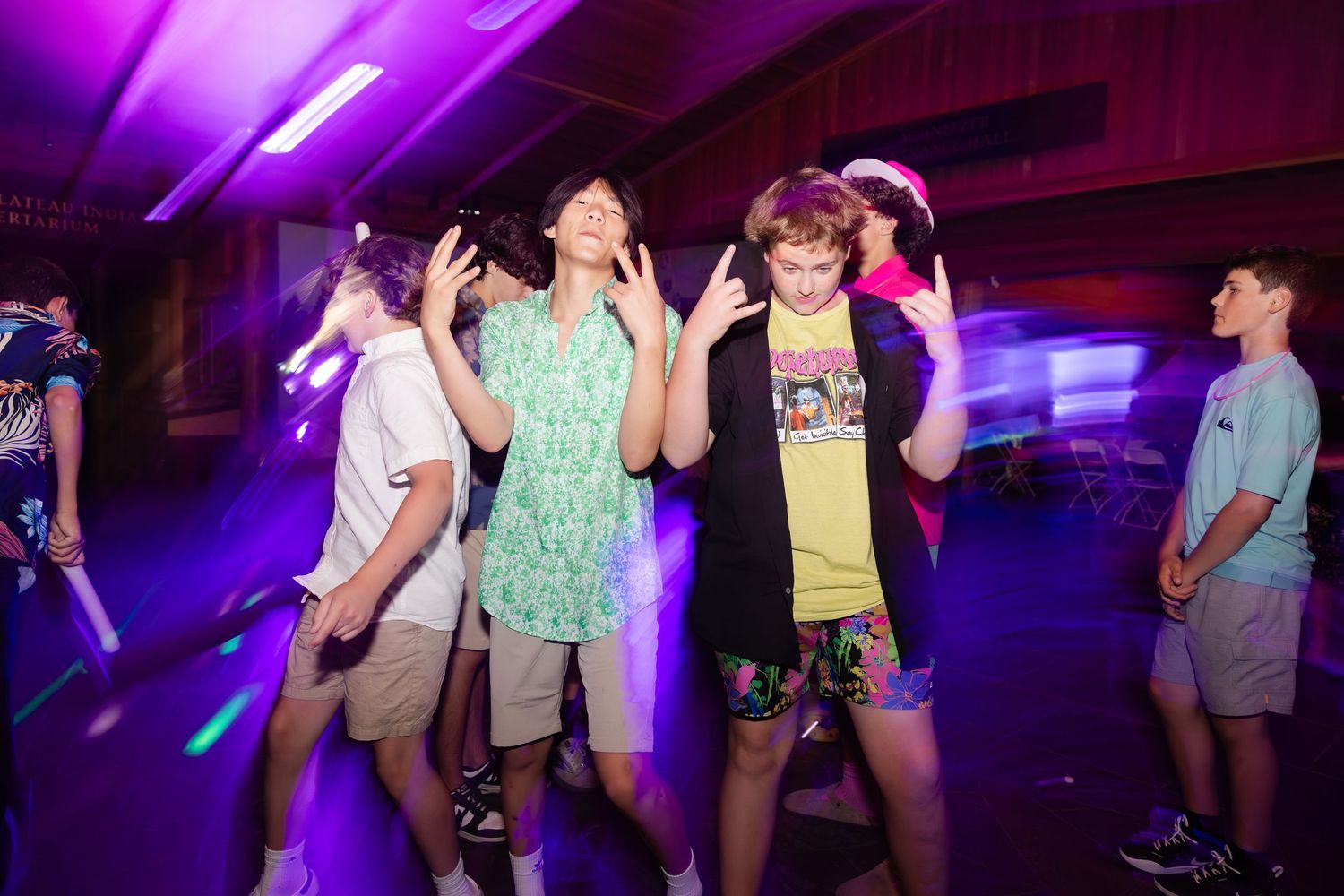 People dancing and having fun in a dark room with purple lighting and party atmosphere.